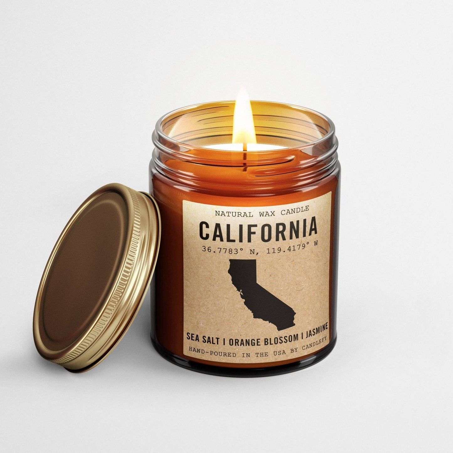 Burning California Homestate Candle in amber glass jar with sea salt, orange blossom, and jasmine scent