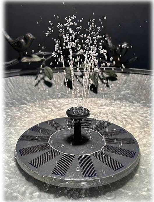 Solar powered fountain disc with water jets and black solar panels floating in water basin