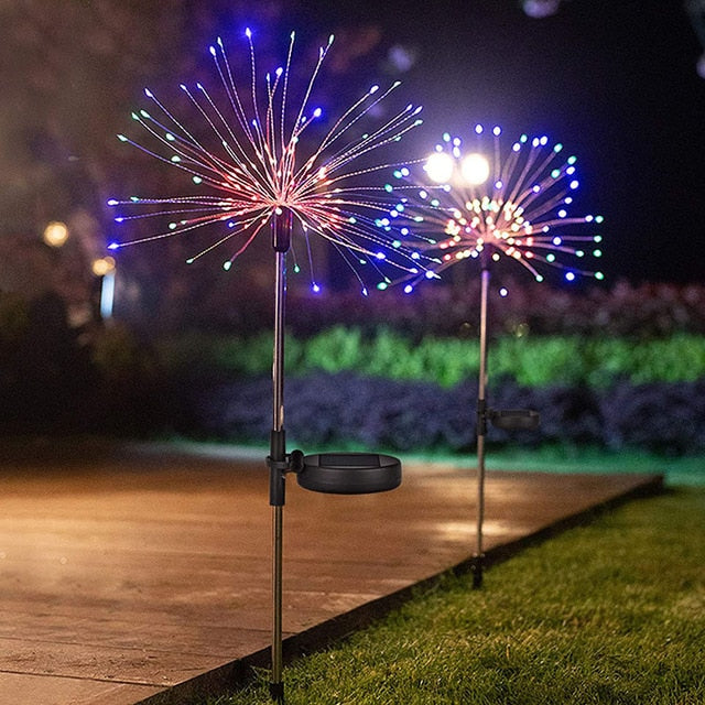 Colorful solar fireworks stake lights with adjustable dandelion-shaped wires glowing in garden at night